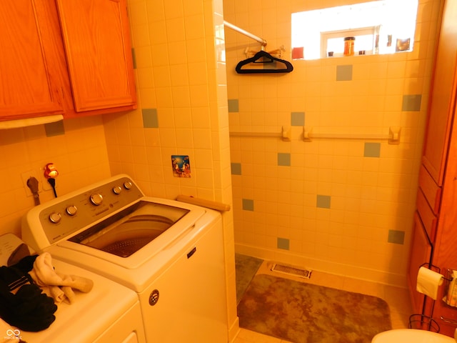 clothes washing area featuring separate washer and dryer, tile patterned flooring, and tile walls