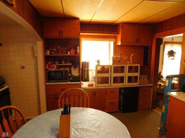 kitchen with a paneled ceiling and wood walls