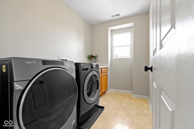 clothes washing area featuring washer and dryer and cabinets