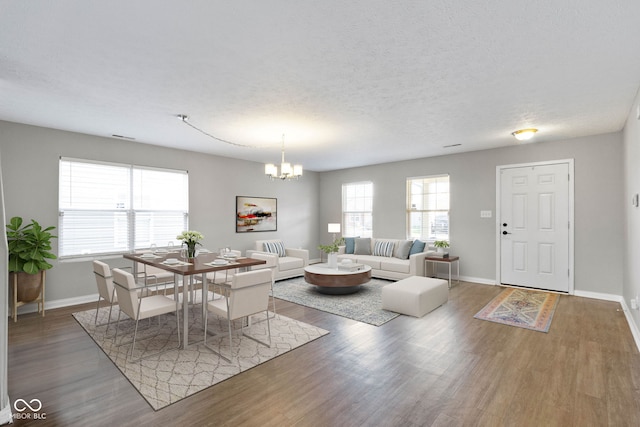 dining area featuring wood-type flooring, a textured ceiling, and a notable chandelier