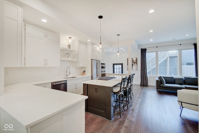 kitchen featuring stainless steel appliances, white cabinetry, sink, dark hardwood / wood-style floors, and a kitchen island