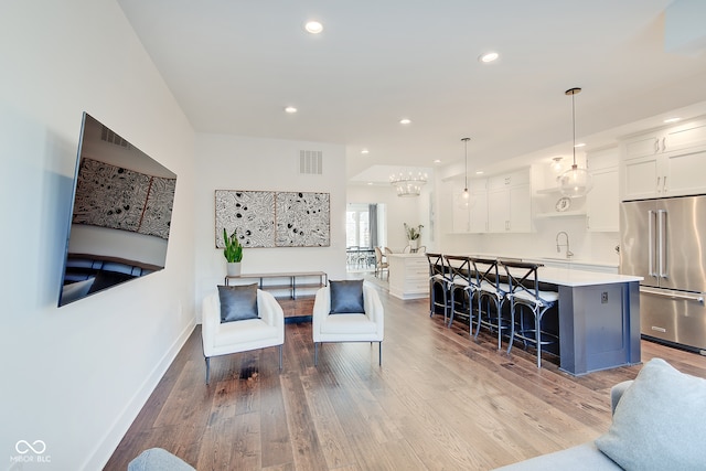 living room featuring an inviting chandelier, light wood-type flooring, and sink