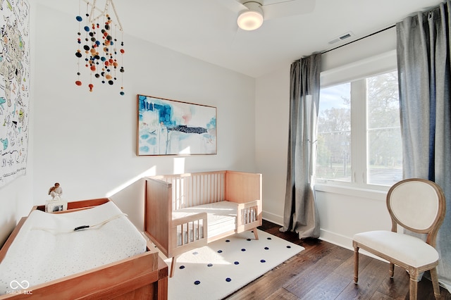 bedroom featuring a crib and dark hardwood / wood-style flooring