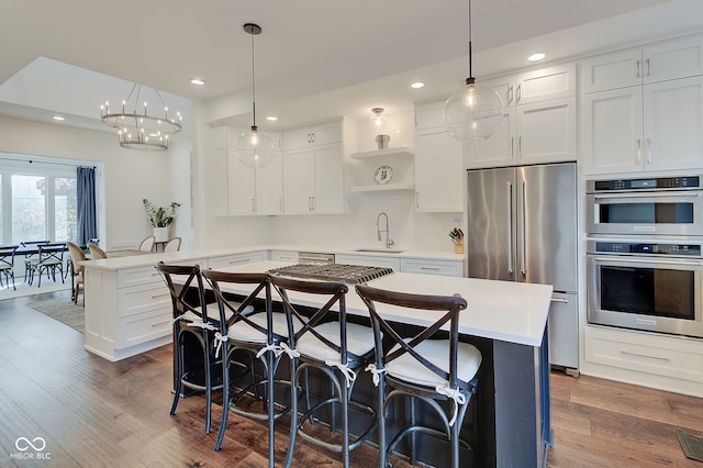 kitchen featuring kitchen peninsula, appliances with stainless steel finishes, hanging light fixtures, and dark hardwood / wood-style floors