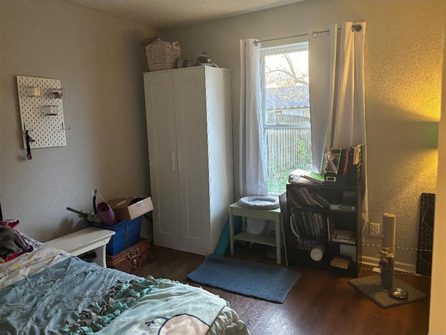 bedroom featuring wood finished floors and a textured wall