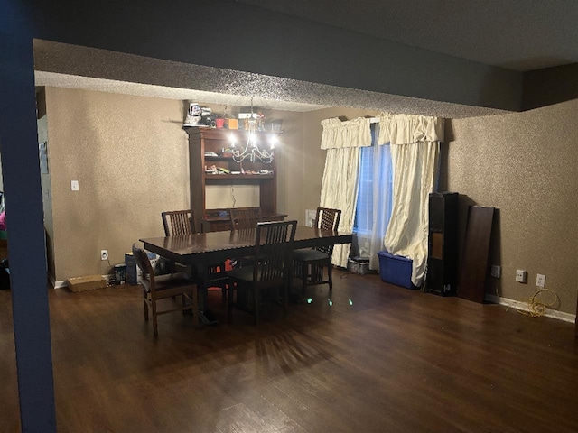 dining area featuring an inviting chandelier, baseboards, wood finished floors, and a textured wall