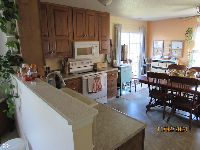 kitchen with white appliances, brown cabinetry, ceiling fan, light countertops, and a textured ceiling
