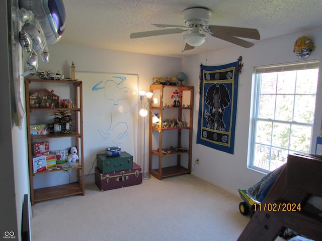 sitting room featuring ceiling fan, carpet, and a textured ceiling