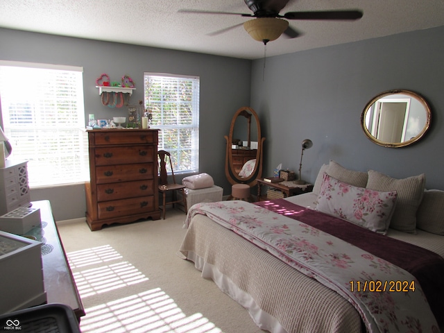 bedroom featuring ceiling fan, a textured ceiling, and light colored carpet