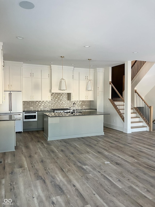 kitchen featuring pendant lighting, white cabinets, built in fridge, and hardwood / wood-style flooring