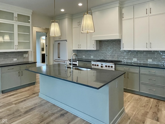 kitchen featuring premium range hood, high end appliances, sink, hanging light fixtures, and an island with sink