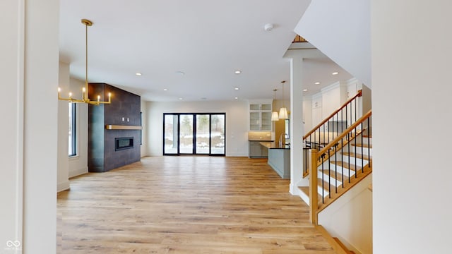 unfurnished living room featuring light hardwood / wood-style floors, a tile fireplace, and an inviting chandelier