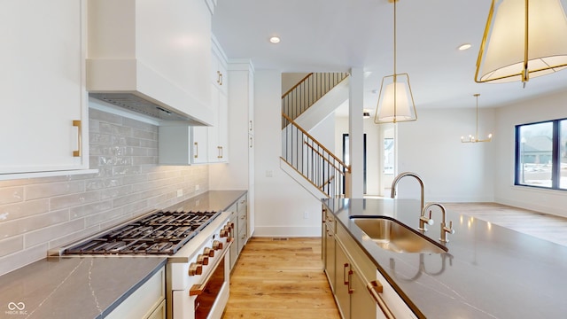 kitchen featuring sink, decorative light fixtures, white cabinetry, and custom exhaust hood