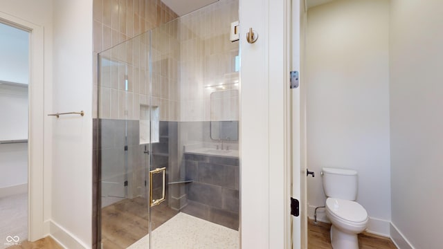 bathroom with a shower with shower door, sink, and toilet