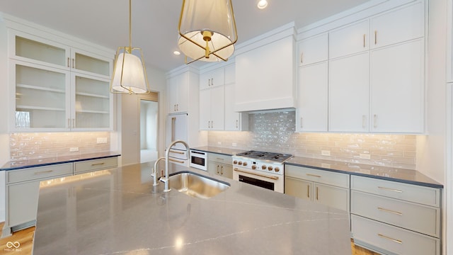 kitchen with premium appliances, white cabinets, custom exhaust hood, and hanging light fixtures