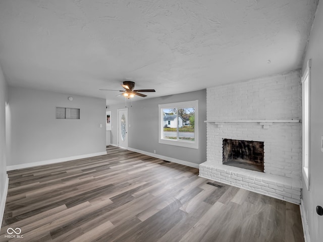 unfurnished living room featuring hardwood / wood-style flooring, ceiling fan, and a fireplace