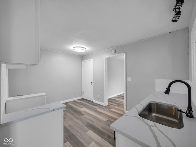 kitchen with white cabinets, light hardwood / wood-style flooring, and sink