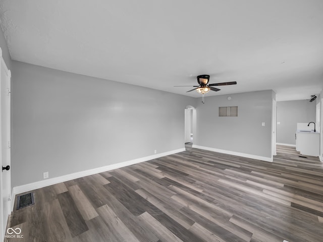 unfurnished living room featuring dark hardwood / wood-style flooring, ceiling fan, and sink