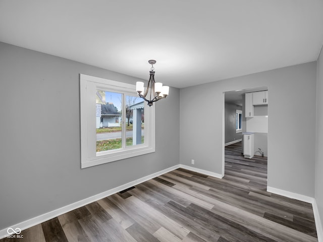 unfurnished dining area with a chandelier and dark wood-type flooring