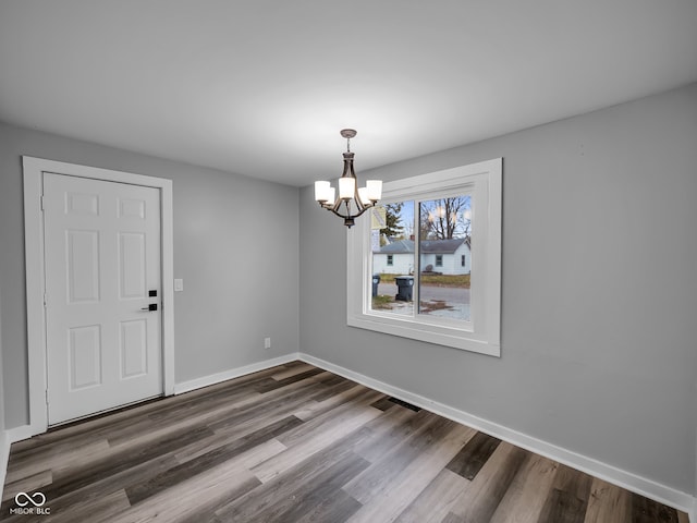 unfurnished dining area featuring dark hardwood / wood-style floors and a notable chandelier