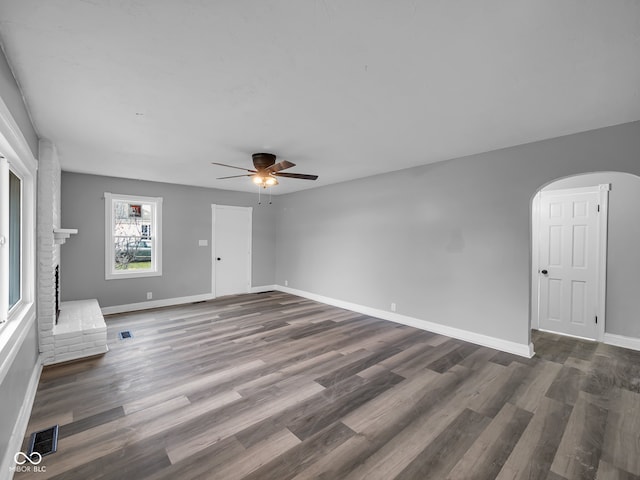 unfurnished living room featuring a fireplace, ceiling fan, and dark hardwood / wood-style flooring