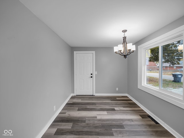 unfurnished dining area with a notable chandelier and dark hardwood / wood-style flooring