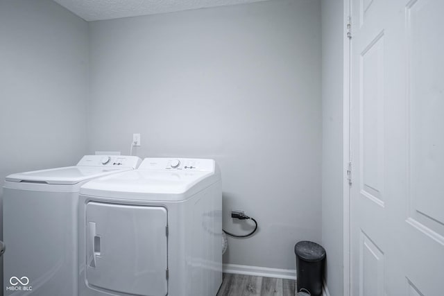 washroom featuring washing machine and dryer, wood-type flooring, and a textured ceiling