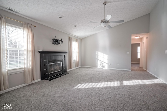 unfurnished living room featuring a tile fireplace, a wealth of natural light, carpet floors, and lofted ceiling