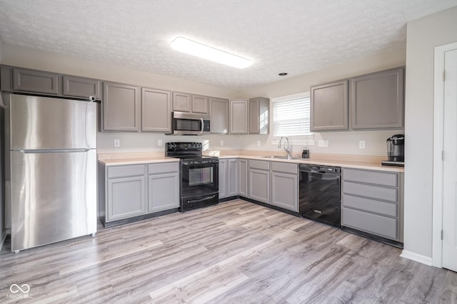 kitchen featuring light wood-type flooring, gray cabinetry, a textured ceiling, sink, and black appliances