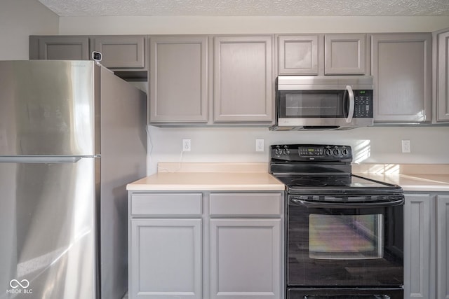 kitchen with a textured ceiling, stainless steel appliances, and gray cabinetry