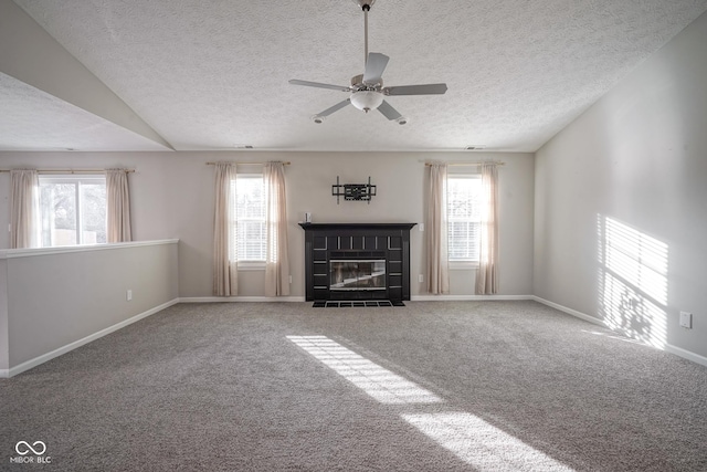 unfurnished living room with carpet, vaulted ceiling, a wealth of natural light, and ceiling fan