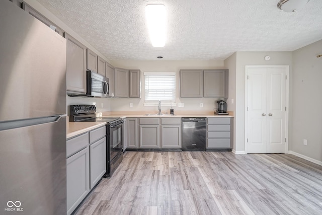 kitchen featuring gray cabinetry, black appliances, sink, a textured ceiling, and light hardwood / wood-style floors