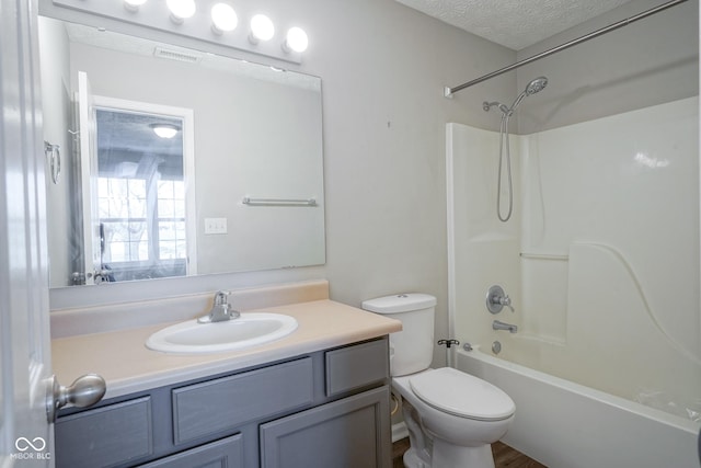 full bathroom with toilet, vanity, a textured ceiling, and washtub / shower combination