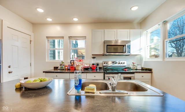 951 W 33rd St, Indianapolis, IN 46208 - kitchen featuring stainless steel appliances, dark countertops, white cabinetry, plenty of natural light, and recessed lighting