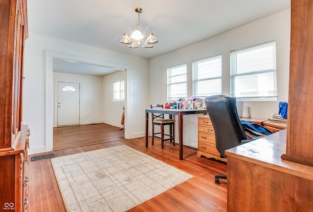 office space with an inviting chandelier and light hardwood / wood-style flooring