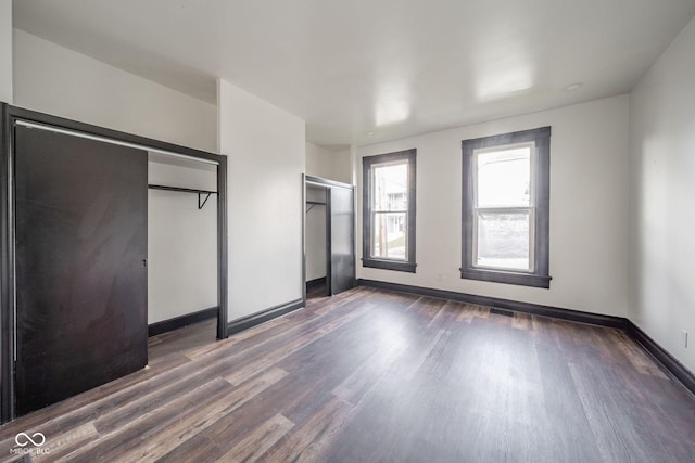 425 Sanders St, Indianapolis, IN 46225 - unfurnished bedroom featuring dark wood-style flooring, baseboards, and two closets