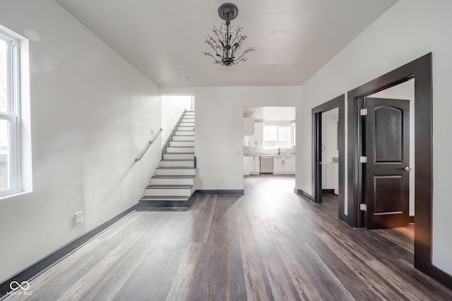425 Sanders St, Indianapolis, IN 46225 - unfurnished living room featuring wood finished floors, stairway, baseboards, and a chandelier