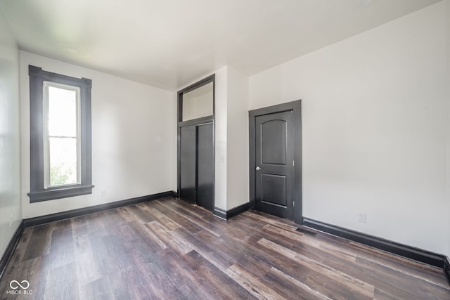 unfurnished bedroom with dark hardwood / wood-style flooring and a closet