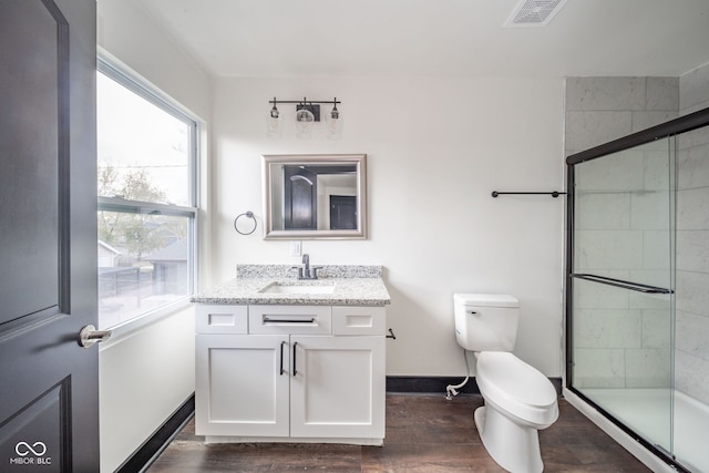 bathroom with toilet, vanity, wood-type flooring, and a shower with door