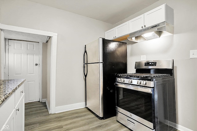 kitchen with white cabinetry, light wood-type flooring, light stone countertops, and appliances with stainless steel finishes