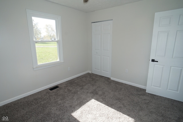 unfurnished bedroom featuring dark colored carpet and a closet