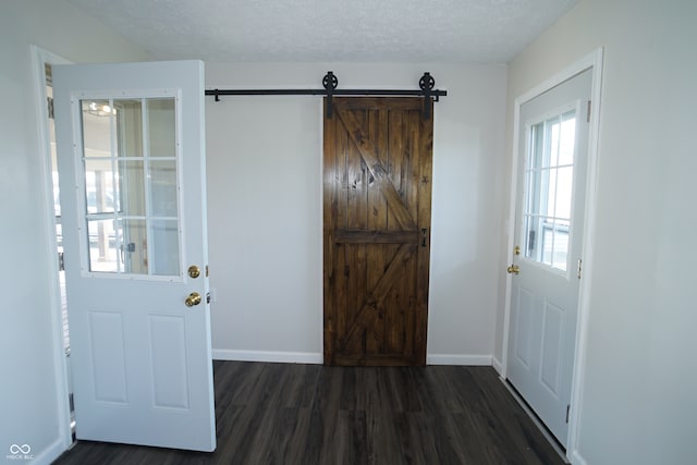 entrance foyer with a barn door, dark hardwood / wood-style floors, and a textured ceiling