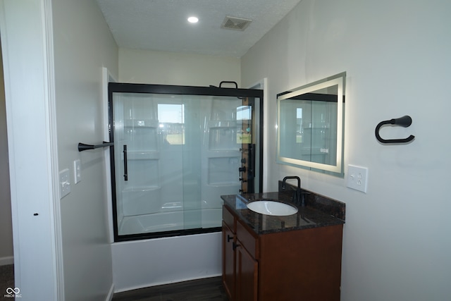 bathroom with vanity, hardwood / wood-style floors, enclosed tub / shower combo, and a textured ceiling