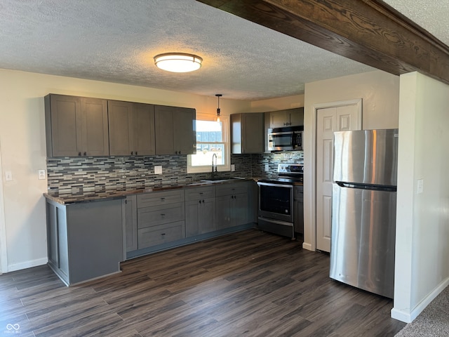 kitchen featuring appliances with stainless steel finishes, hanging light fixtures, and dark hardwood / wood-style floors