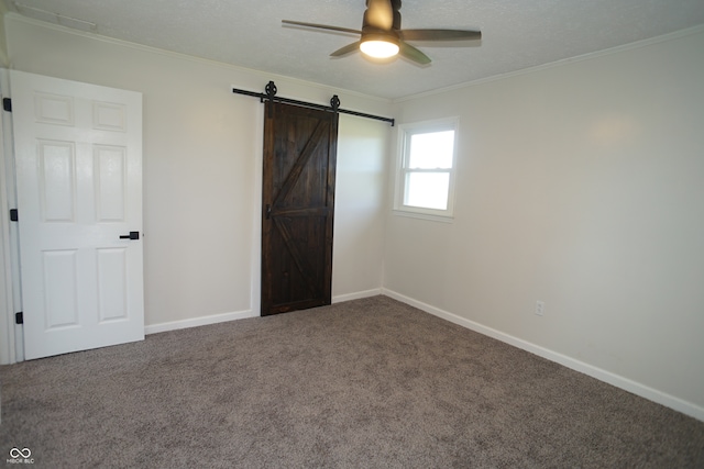 unfurnished bedroom with a barn door, ceiling fan, carpet flooring, and ornamental molding