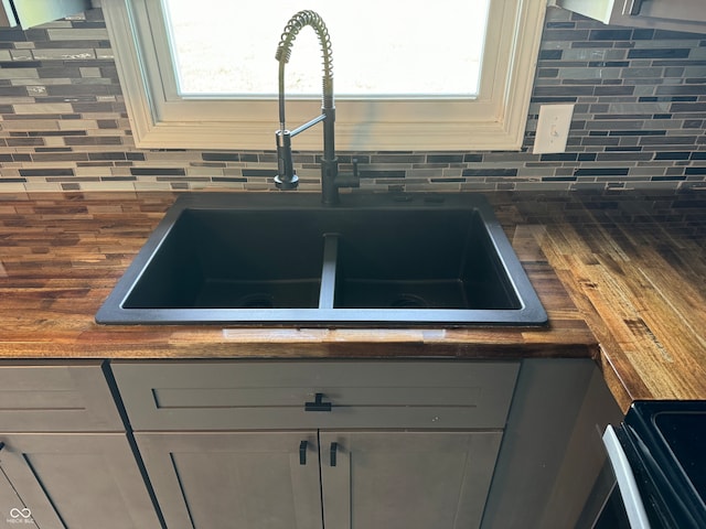 interior details featuring tasteful backsplash, sink, and wood counters