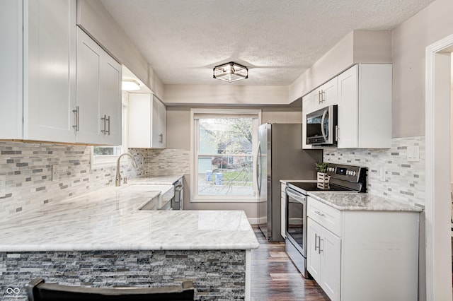 5909 Buttonwood Dr, Noblesville, IN 46062 - kitchen featuring stainless steel appliances, a textured ceiling, dark wood-style floors, white cabinets, and a peninsula