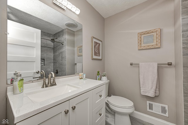 5909 Buttonwood Dr, Noblesville, IN 46062 - bathroom with a tile shower, a textured ceiling, toilet, vanity, and baseboards