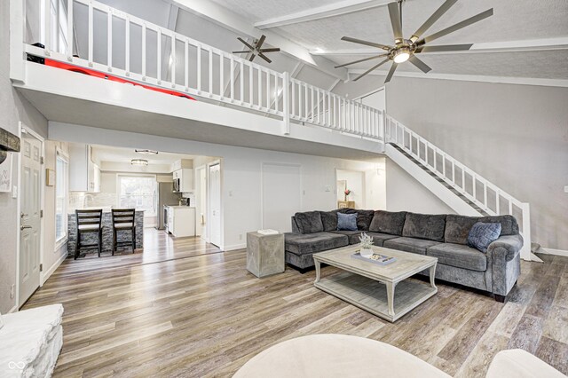 5909 Buttonwood Dr, Noblesville, IN 46062 - living area featuring a ceiling fan, high vaulted ceiling, light wood finished floors, stairway, and beam ceiling