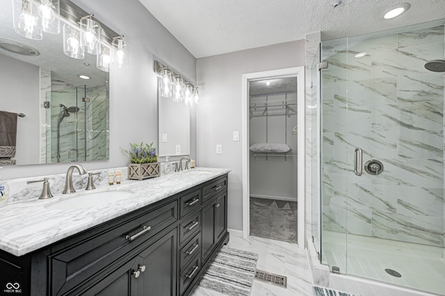 5909 Buttonwood Dr, Noblesville, IN 46062 - bathroom featuring marble look tile flooring, a marble finish shower, a textured ceiling, a walk in closet, and double vanity